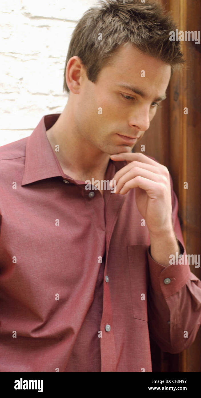 Male Short Brown Hair Wearing Dark Red Shirt Open At Neck Leaning