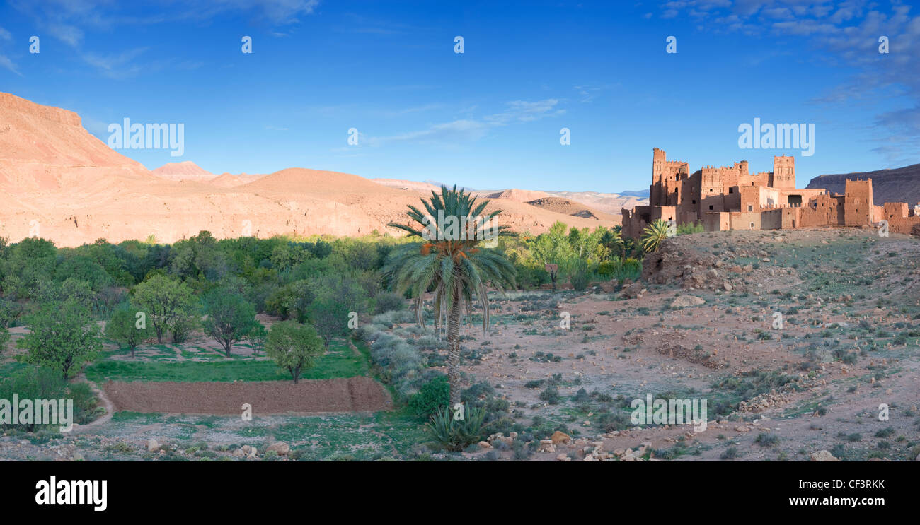 Kasbah Ellouze perched on a rocky outcrop overlooking the date palms and distant Atlas mountains. Stock Photo