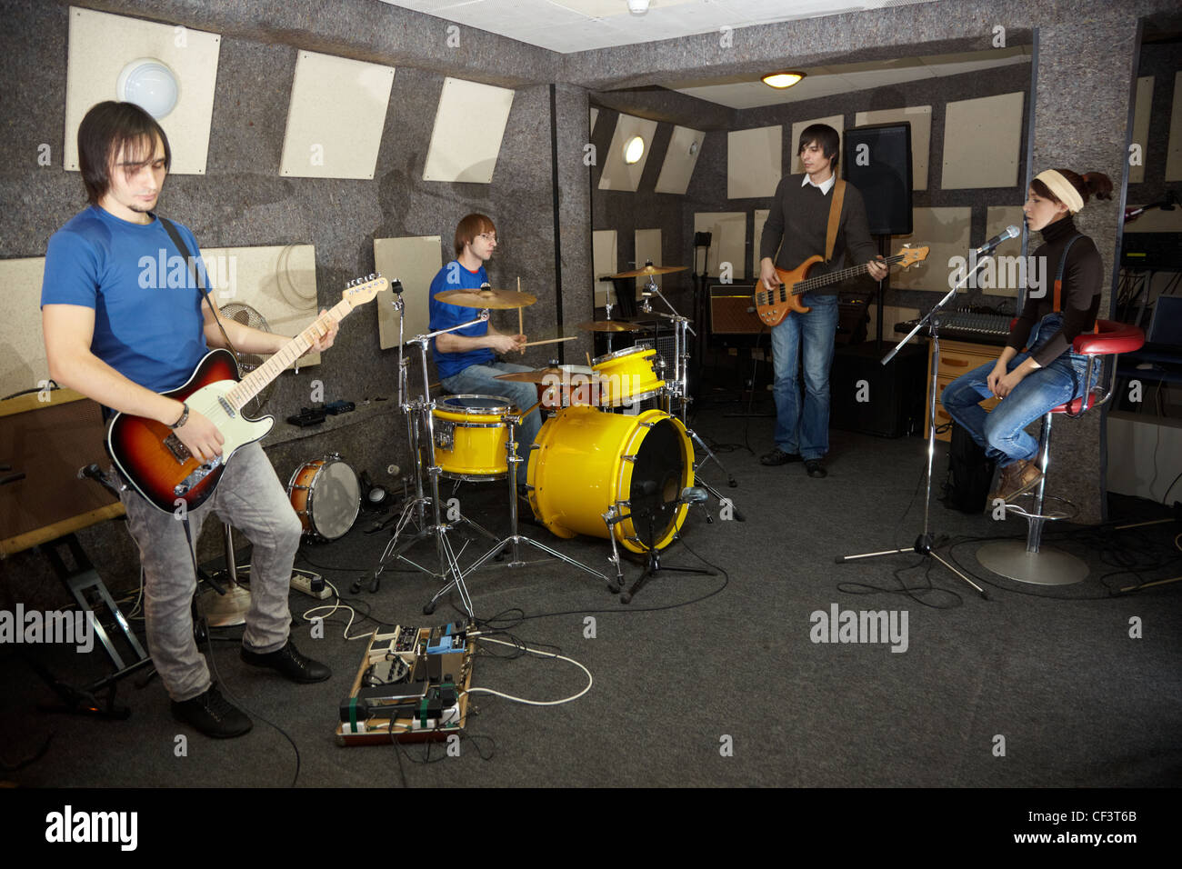 a rock band. vocalist girl, two musicians with electro guitars and one drummer is working in studio Stock Photo