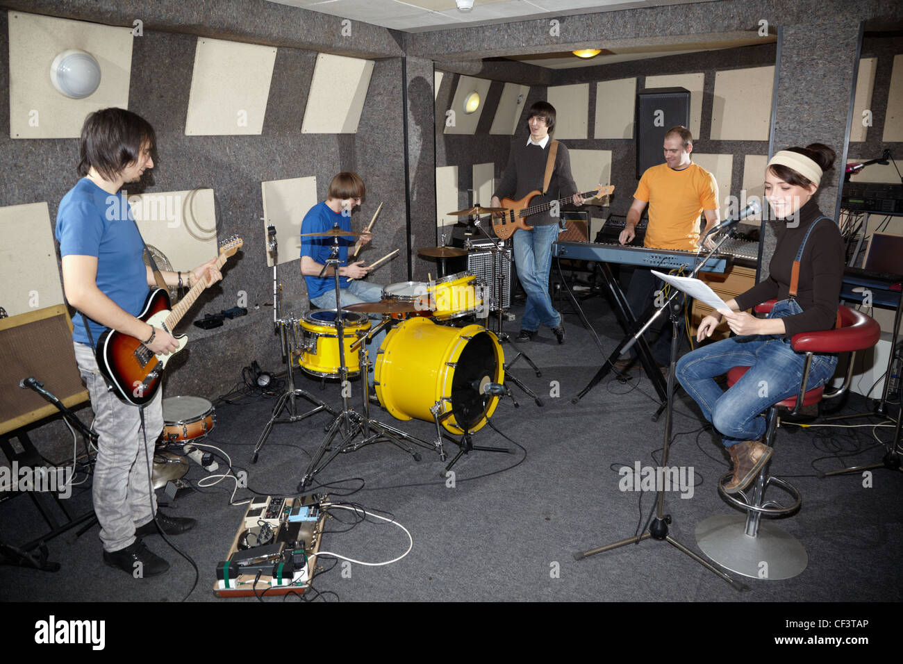 a rock band. vocalist girl, two musicians with electro guitars, keyboarder and one drummer working in studio Stock Photo