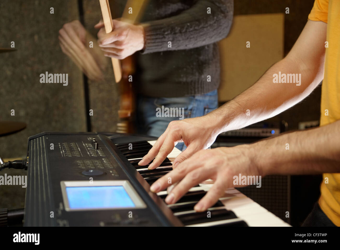 keyboard player playing in studio. guitar player in out of focus Stock