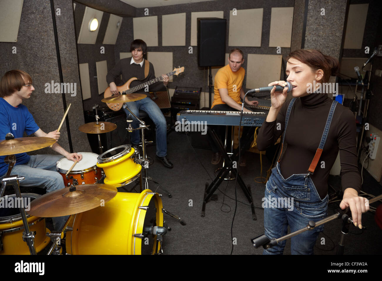 a rock band working in studio. vocalist girl is singing. focus on clothers of vocalist girl Stock Photo