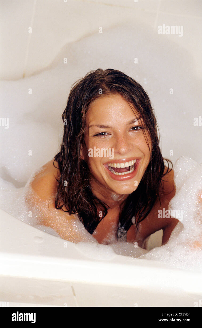 Female With Long Wet Brunette Hair In Bath With Bubble Bath Looking To