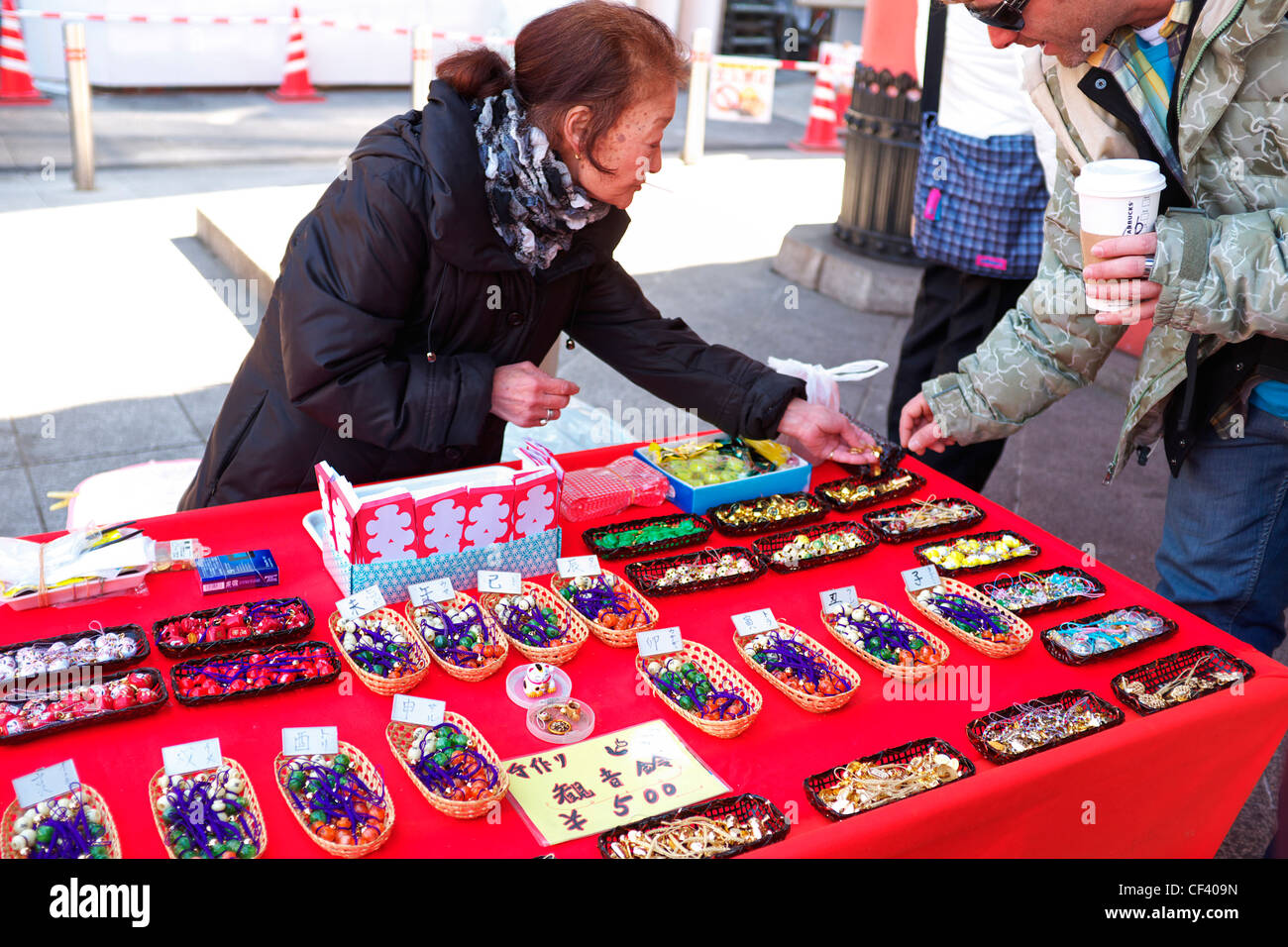 Japanese Woman selling to American Tourist on the Nakamise Dori in front of the Sensoji Temple in Tokyo, Japan Stock Photo