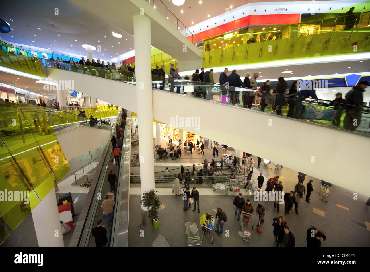 View from escalator in many-storeyed shopping centre and crowd of buyers Stock Photo