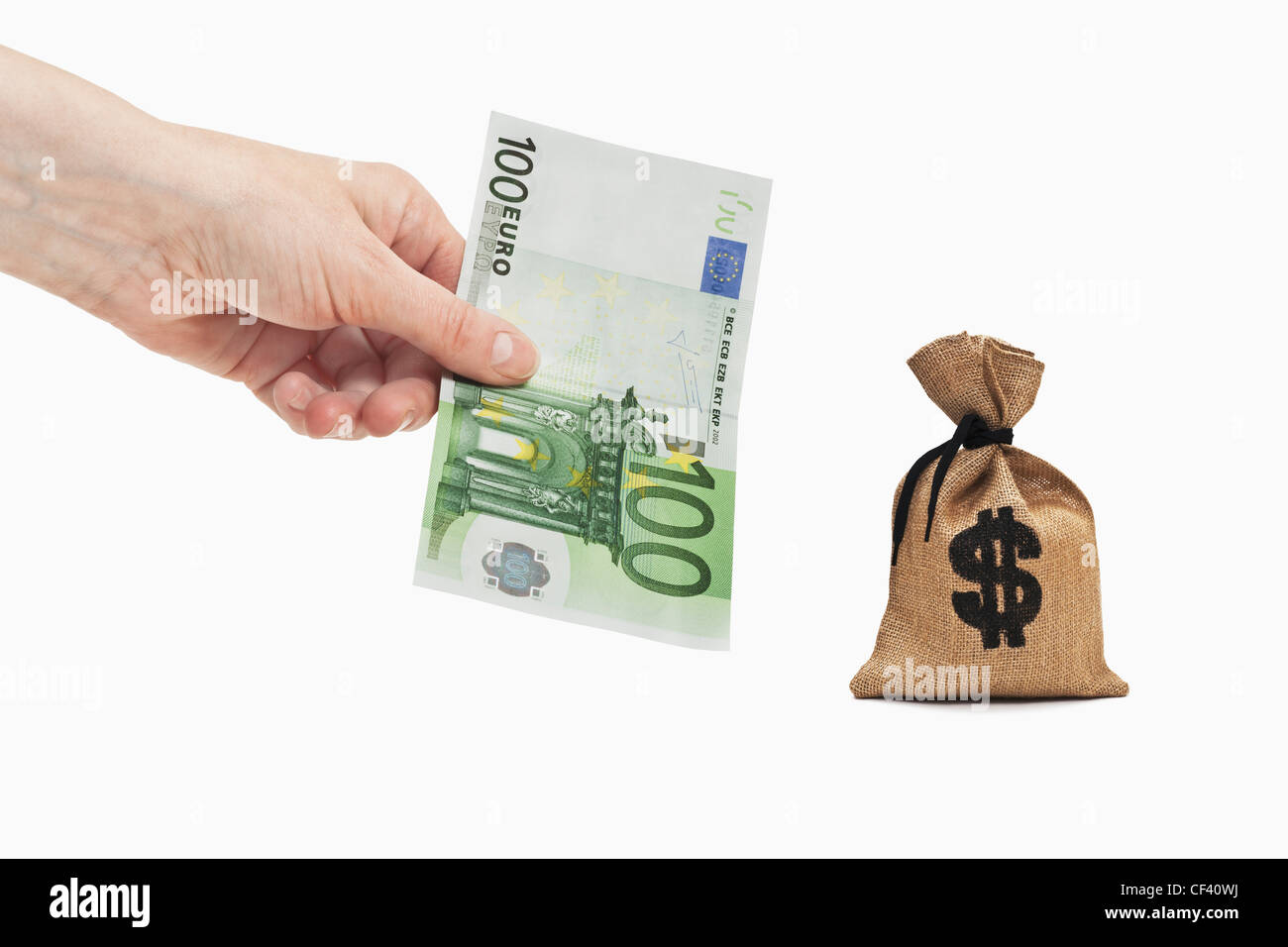 A 100 Euro bill is held in the hand. Near by is a money bag with a U.S. Dollar currency sign. Stock Photo
