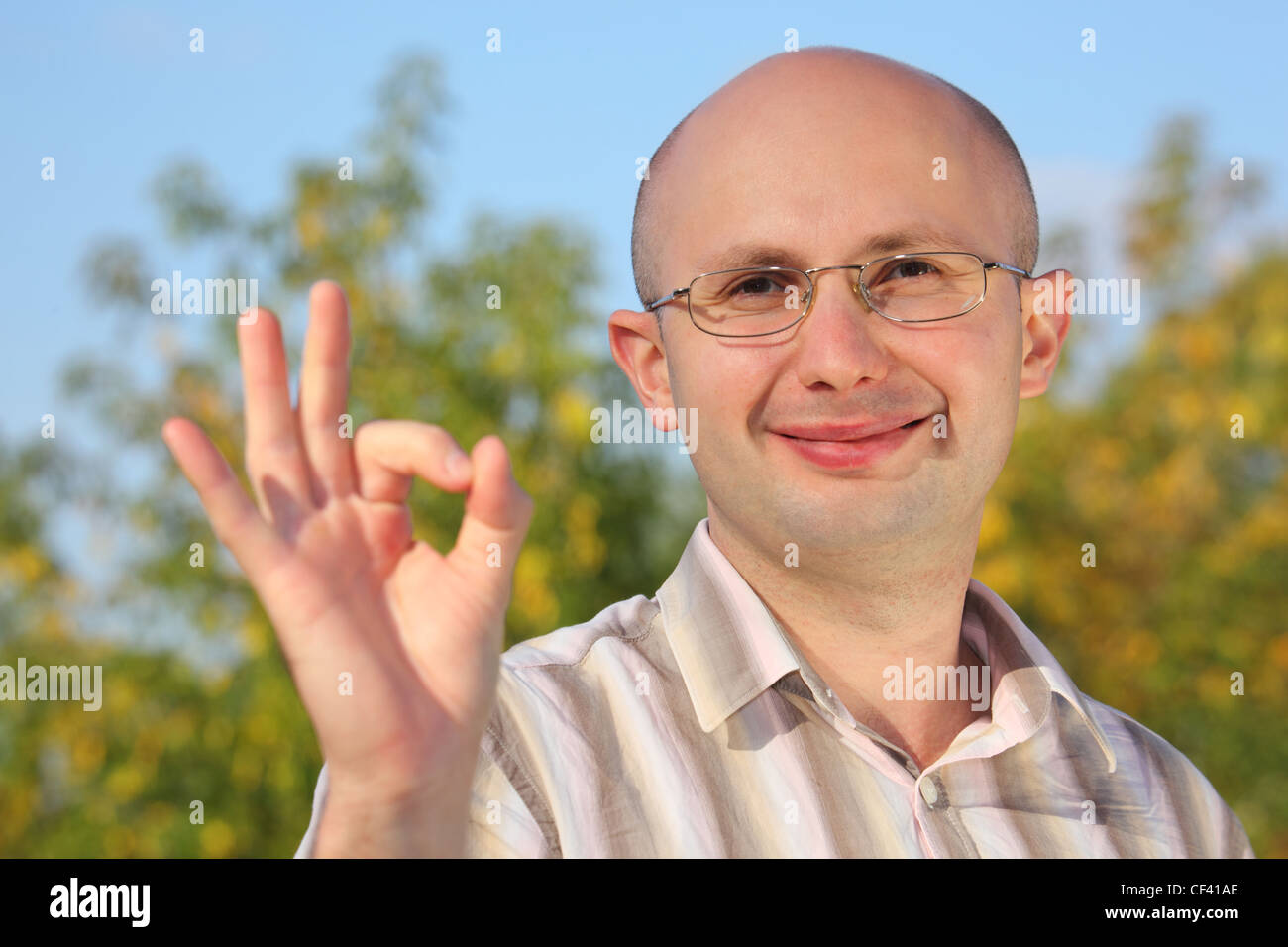 smiling man in early fall park with OK hand gesture Stock Photo
