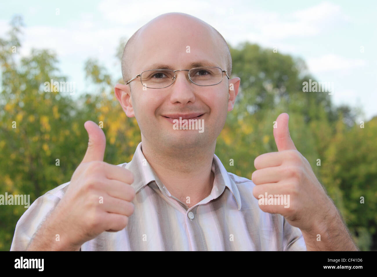 smiling man in early fall park with thumbs up gestures Stock Photo