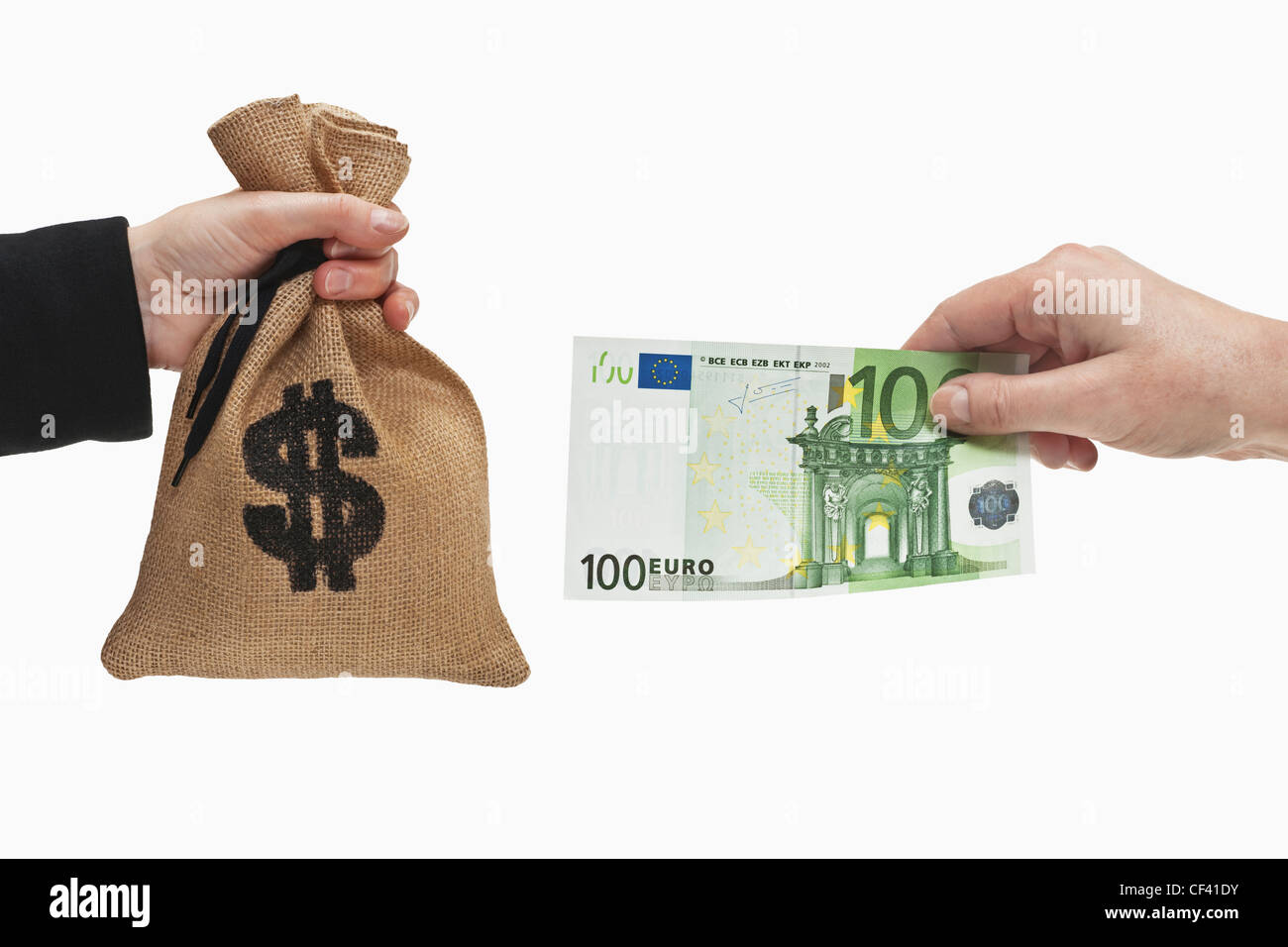 A 100 Euro bill is held in the hand. At the other side a money bag with a U.S. Dollar currency sign is held in the hand. Stock Photo