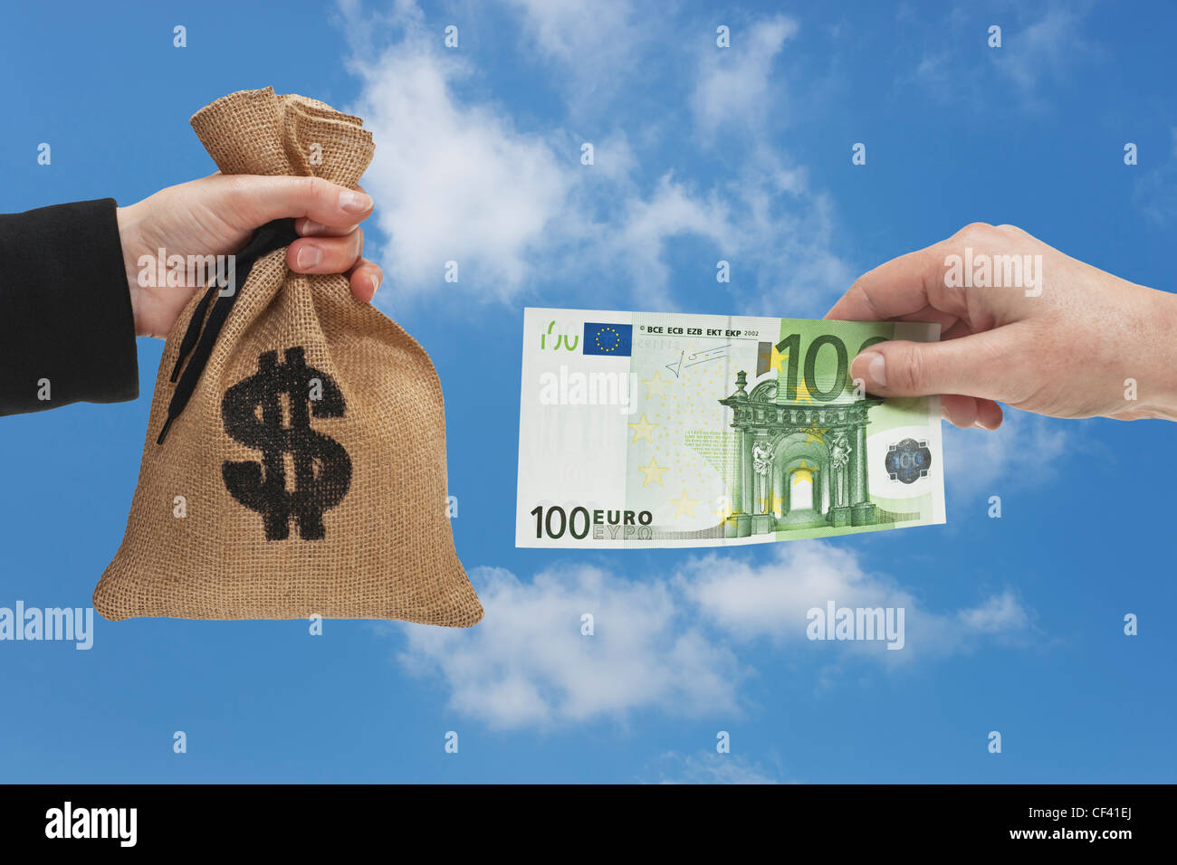 A 100 Euro bill is held in the hand. At the other side a money bag with a U.S. Dollar currency sign is held in the hand. Stock Photo