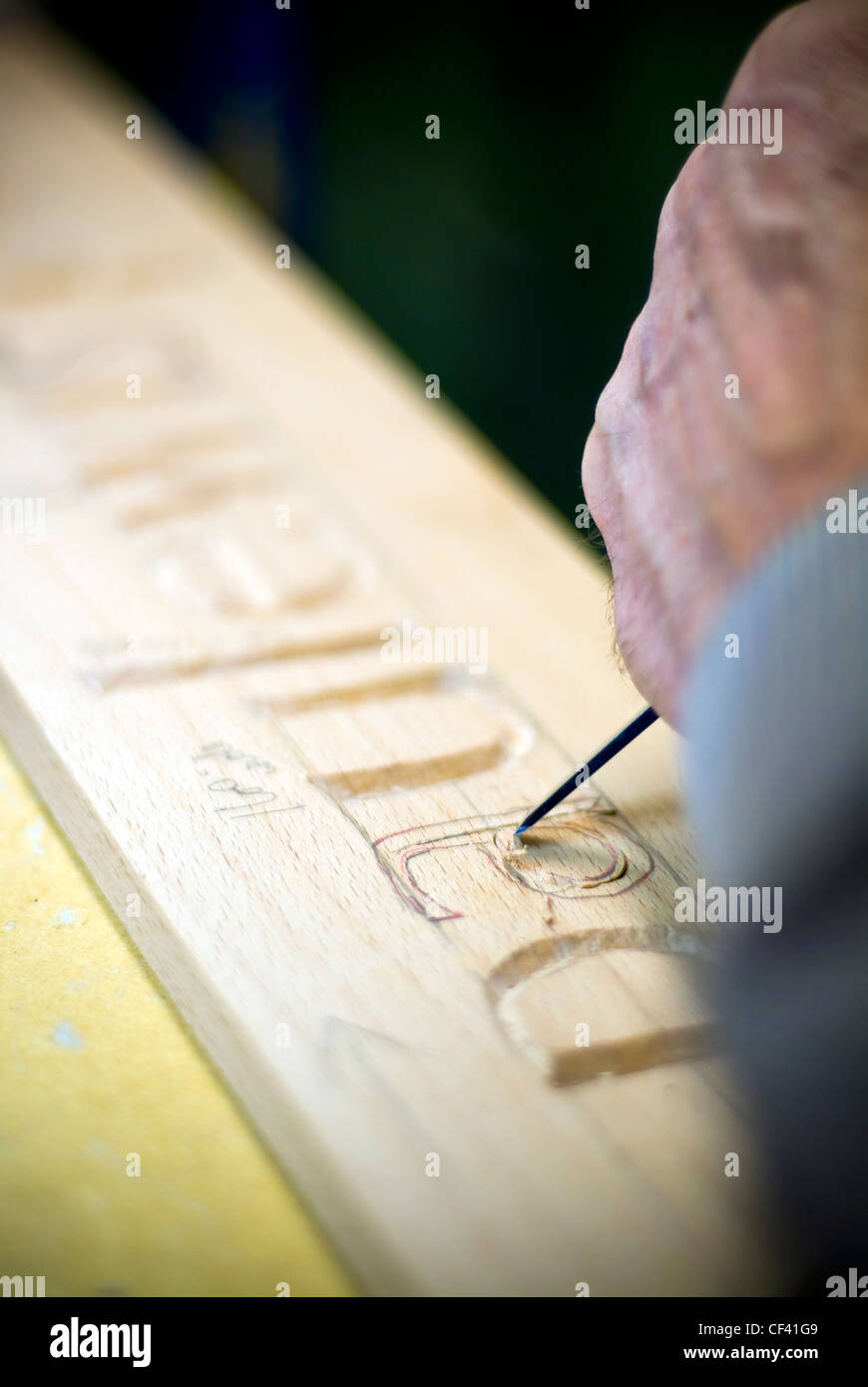 Craftsman carving lettering into wood with a chisel Stock Photo Alamy