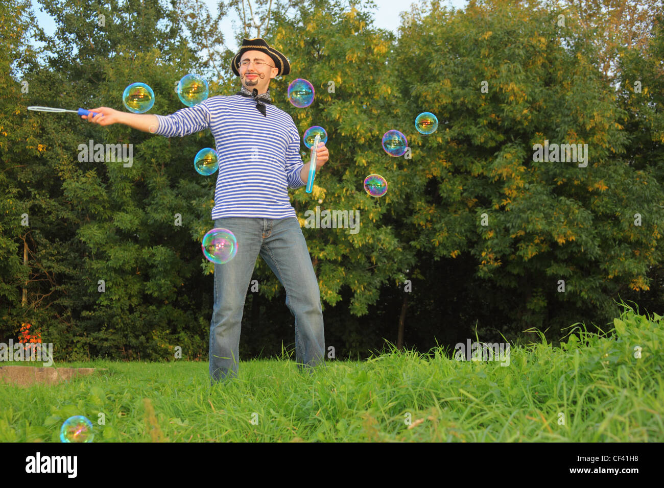 man with drawed beard and whiskers in pirate suit is blowing soap bubbles. Stock Photo