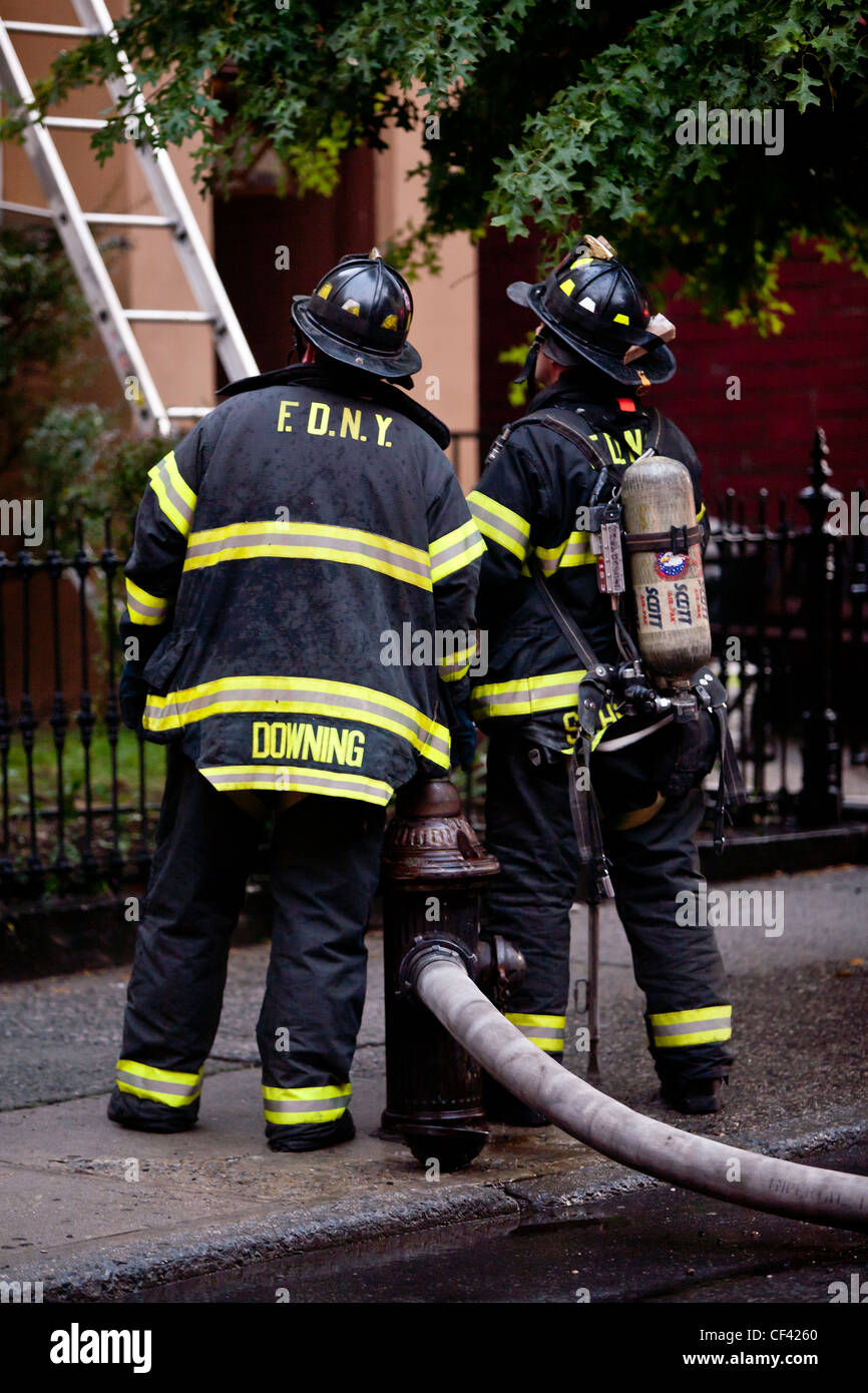 Firemen getting ready to climb the latter to put down fire in one of the townhouses in Brooklyn, NY Stock Photo