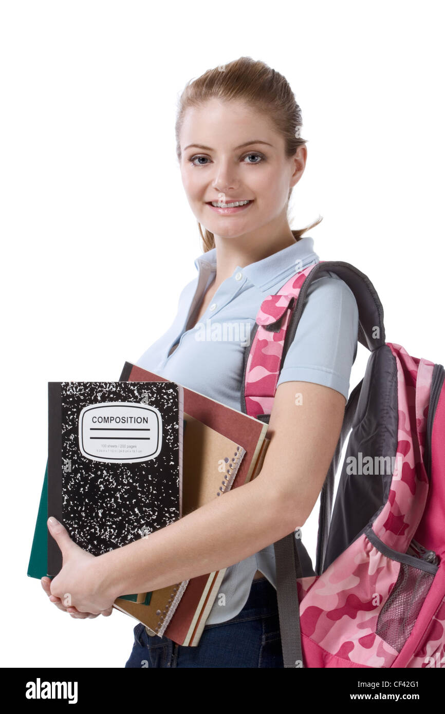 Friendly Caucasian High school girl student standing with backpack and holding books, notebooks and composition book Stock Photo