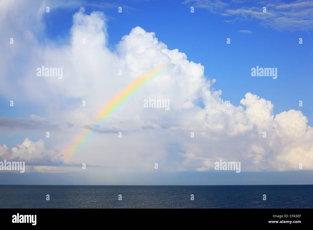 white big clouds and multi-coloured  rainbow over sea in afternoon Stock Photo