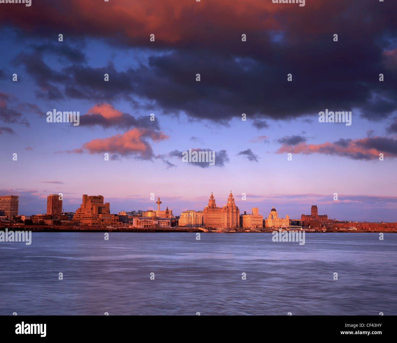 View across the River Mersey towards the Three Graces on the Liverpool waterfront at sunset. Stock Photo