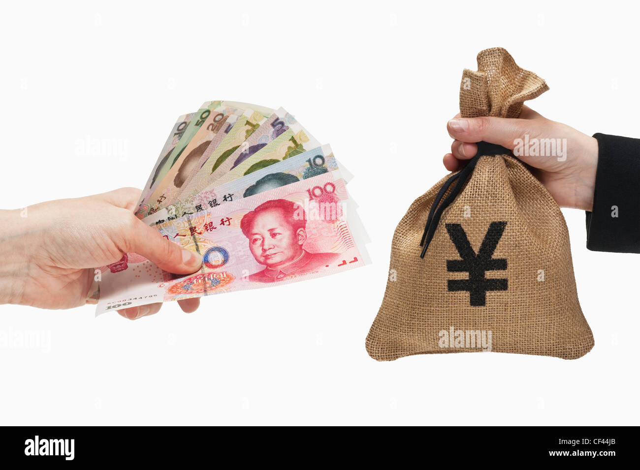 Diverse Chinese Yuan bills are held in the hand. At the other side a money bag with a Japanese Yen currency sign hand held. Stock Photo
