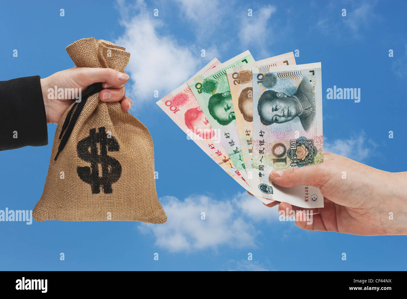 Diverse Chinese Yuan bills are held in the hand. At the other side a money bag with a U.S. Dollar currency sign held in the hand Stock Photo