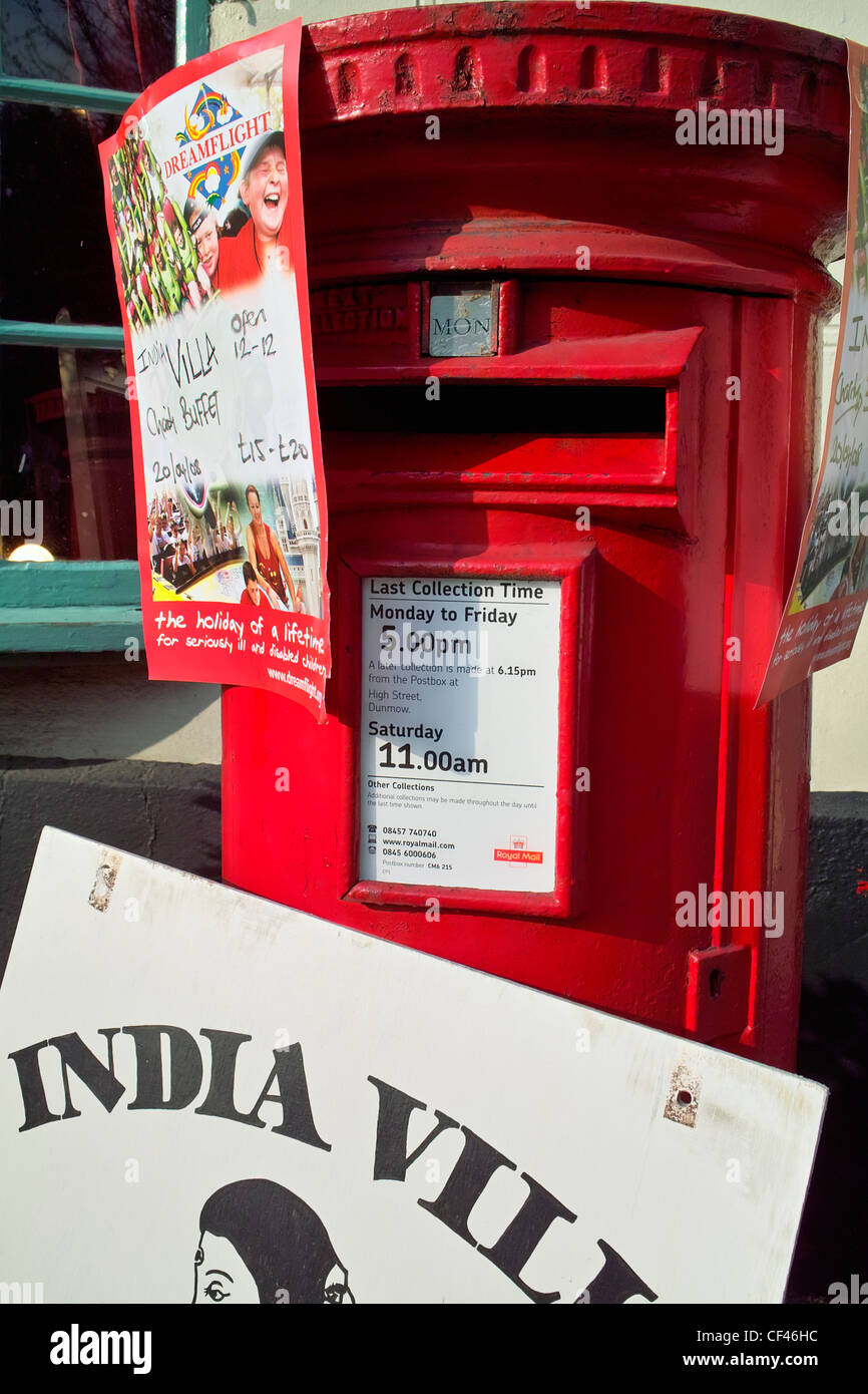 A red post box adorned with signs of a local Indian restaurant in Thaxted. Stock Photo