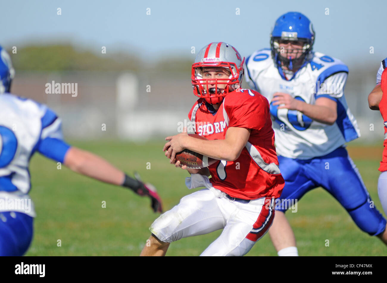 A quarterback looks for running room during a scramble from the pocket during a high school football game. USA. Stock Photo