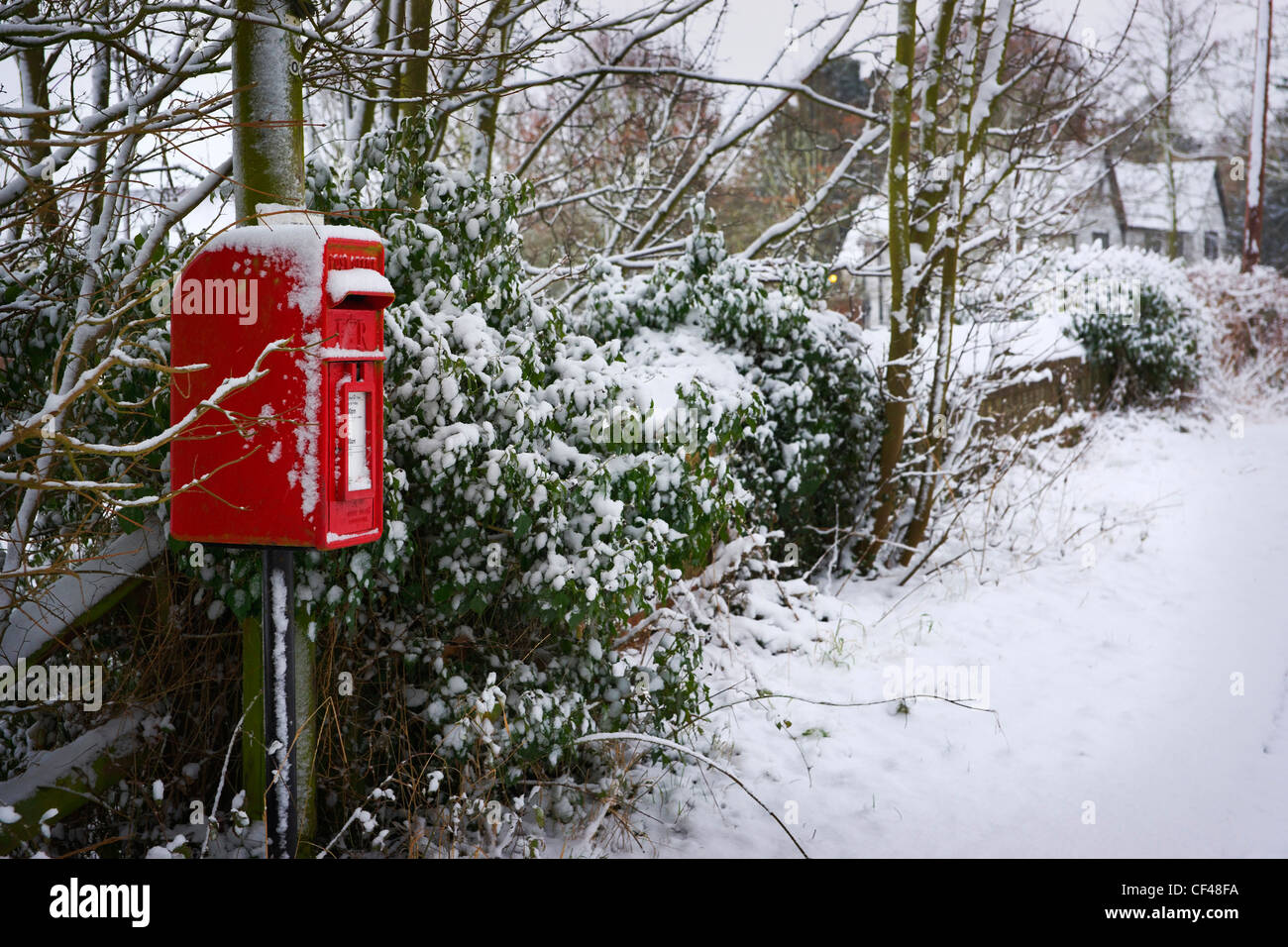 A winter scene with snow covering a red post box in Saffron Walden. Stock Photo