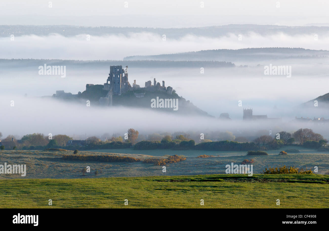 Corfe Castle commanding a gap in the Purbeck Hills shrouded in mist. Stock Photo