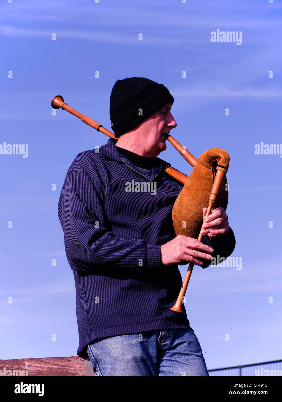 Busker man playing bagpipes with a single drone on Whitby West Cliff (possibly Swedish pipes) Stock Photo
