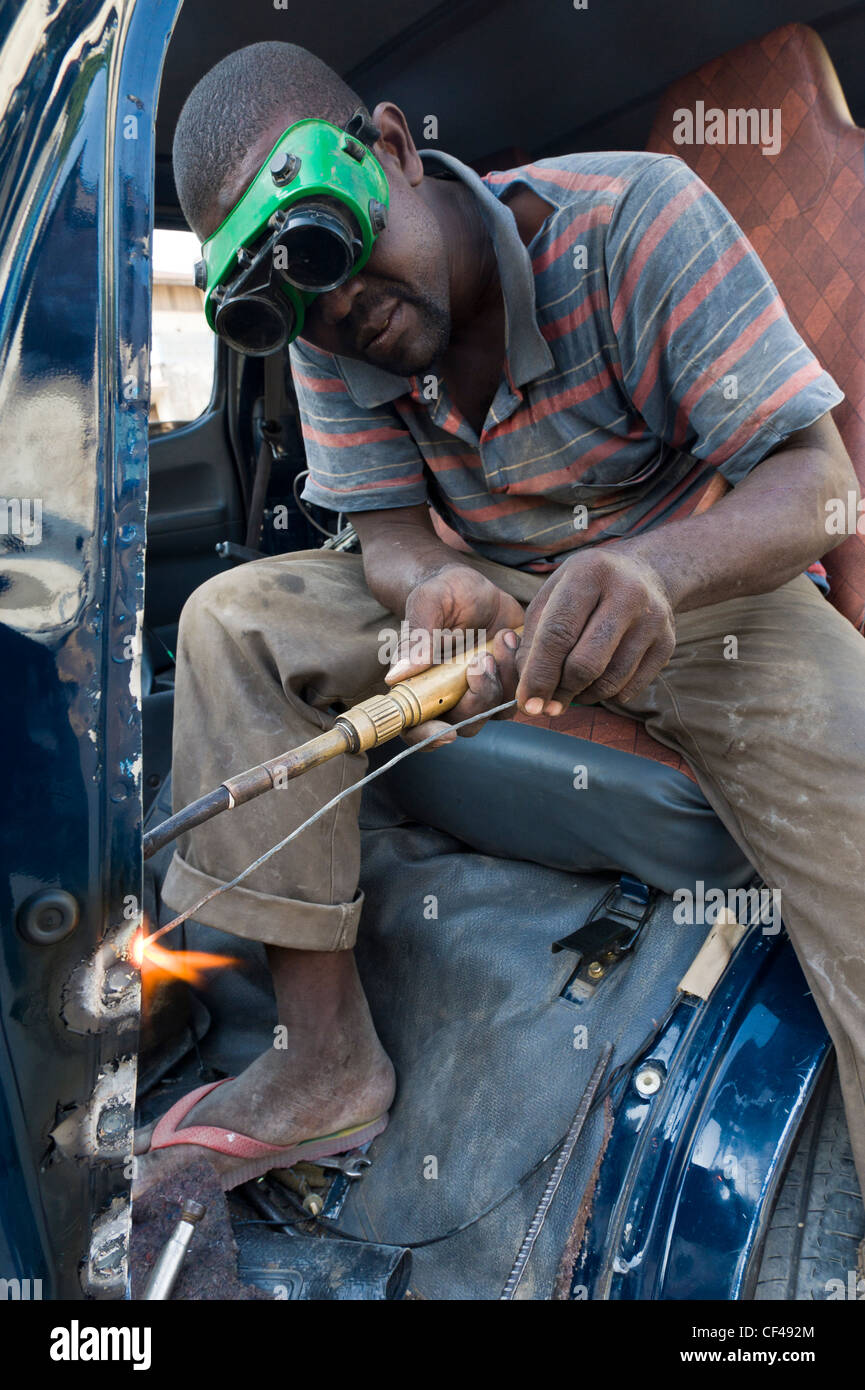 Welder repairing a crashed minibus in Stone Town Zanzibar Tanzania Stock Photo