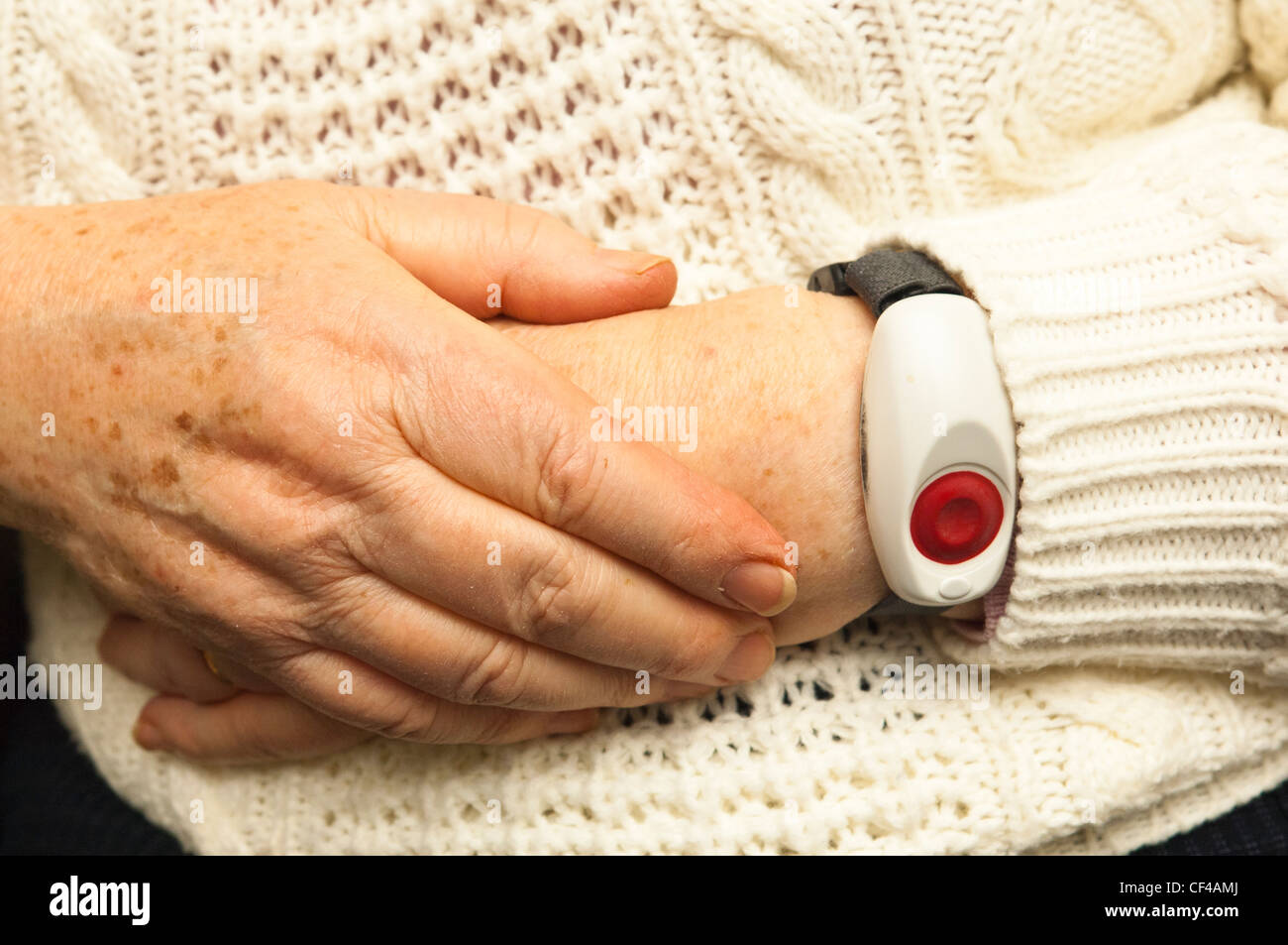 A senior elderly woman in her 70's with a home alarm unit on her wrist for emergencies at home in England , Britain , Uk Stock Photo