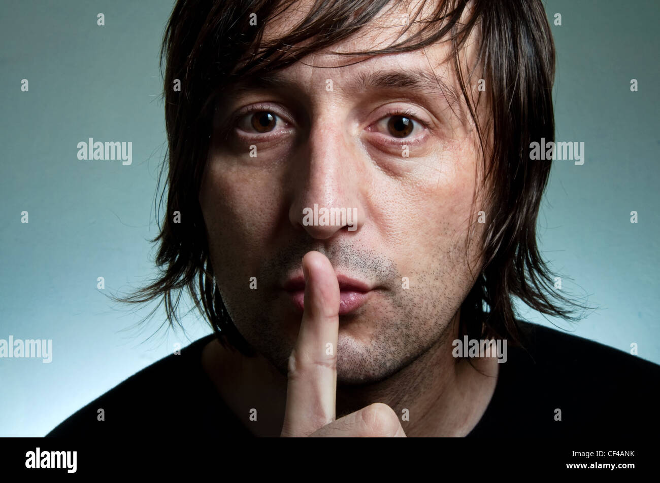 MAn holding a finger over his mouth making silent gesture. Stock Photo