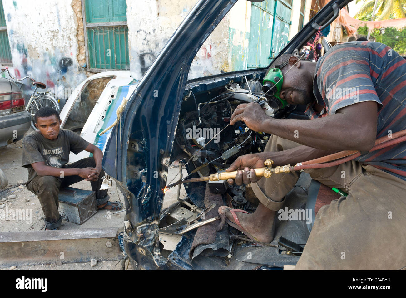Welder repairing a crashed minibus in Stone Town Zanzibar Tanzania Stock Photo