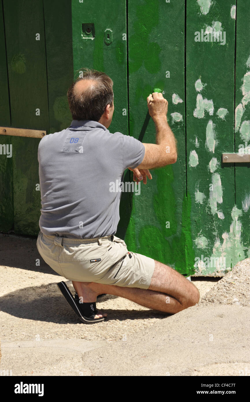 Man painting a door green in the fishing village of Cala Figueras Majorca Spain Stock Photo