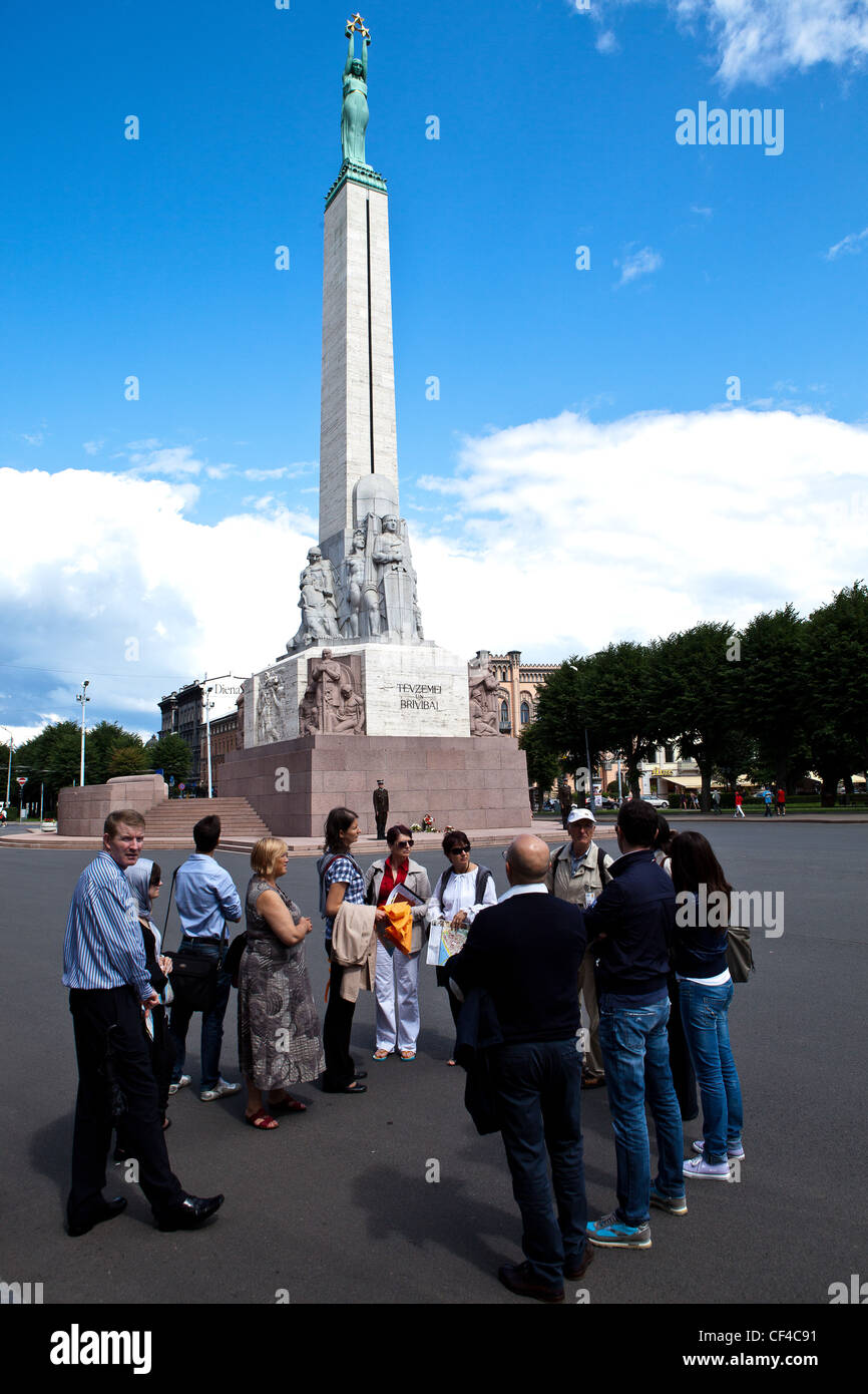 A group of tourists standing before the Freedom Monument, Riga, Latvia, Baltic States, Europe Stock Photo