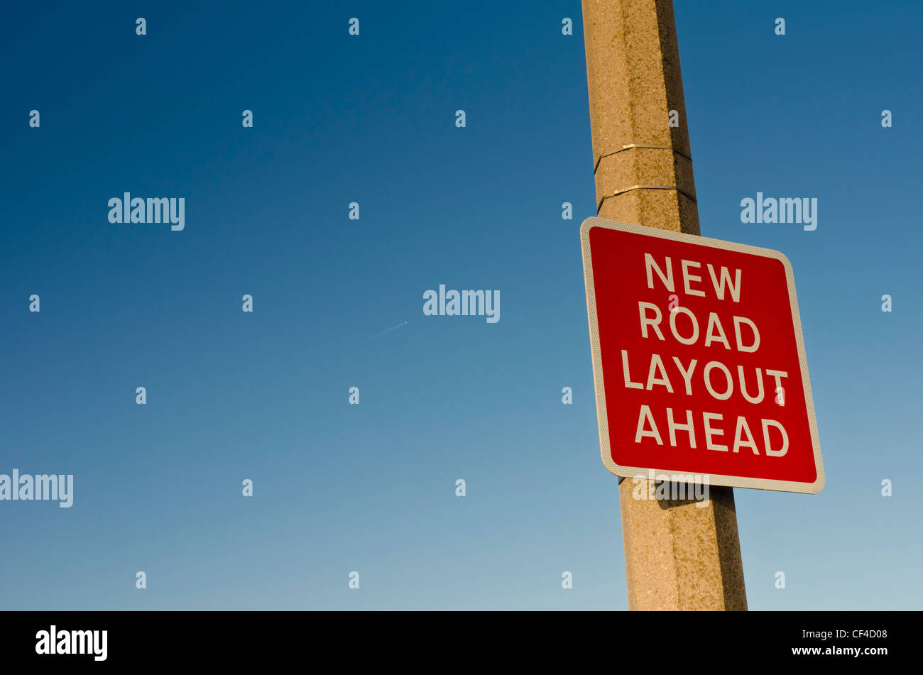 New road layout ahead on a concrete lamp post against a clear blue sky Stock Photo