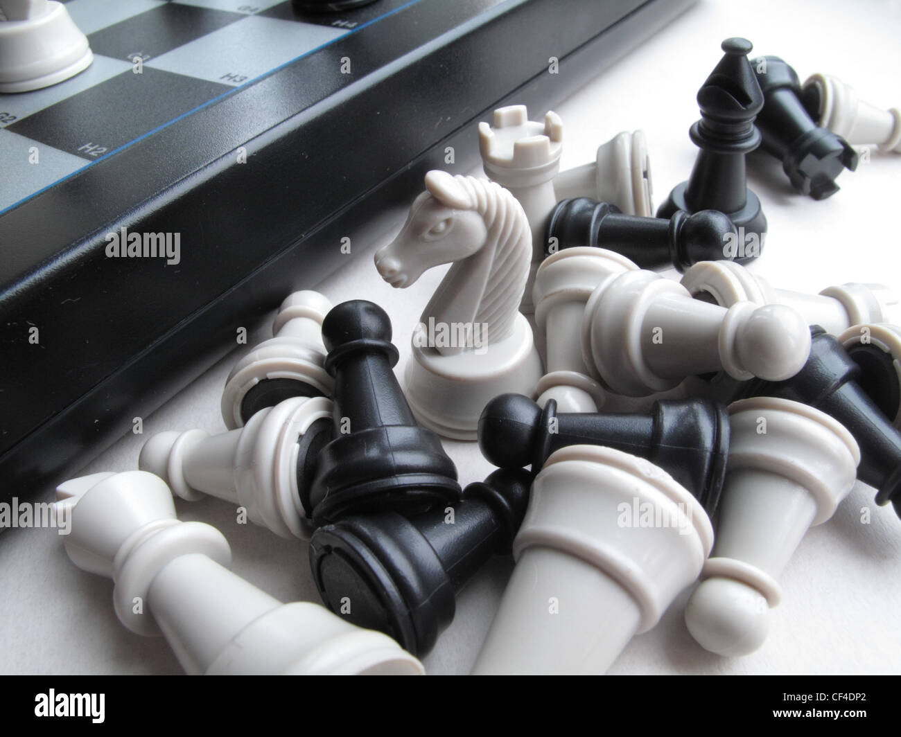 black and white captured chess pieces - rook, pawns  - lie at the side of a chess board. Stock Photo