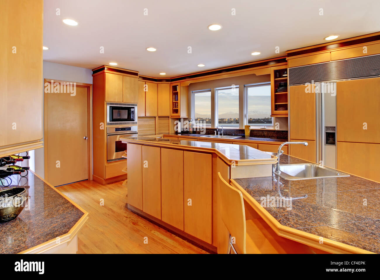 A modern farmhouse kitchen with white cabinets, a wood island with chairs,  Viking stainless steel appliances, and a dark granite countertop Stock  Photo - Alamy