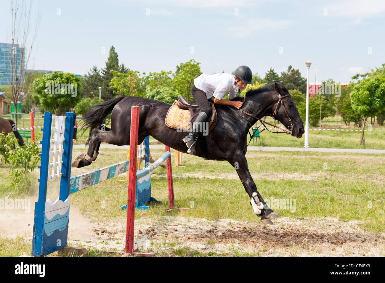 Jockey on black horse jumping in a public jump show. Stock Photo