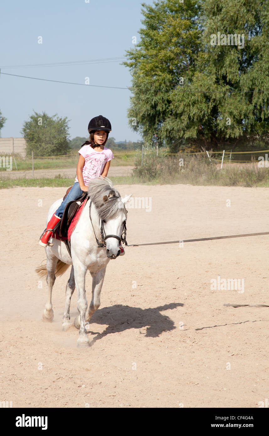 Little girl riding a horse and taking horse back riding lessons ...