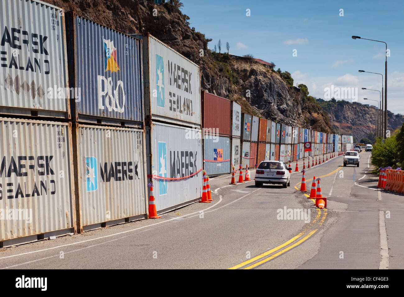 A line of shipping containers protects Main Road in the Christchurch suburb of Sumner from rockfalls Stock Photo