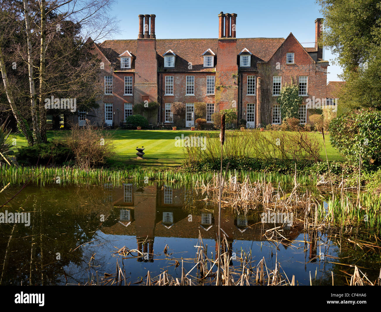 The rear of Hintlesham Hall, a stunning 16th century Elizabethan Grade I listed country house hotel, reflected in a pond in the Stock Photo
