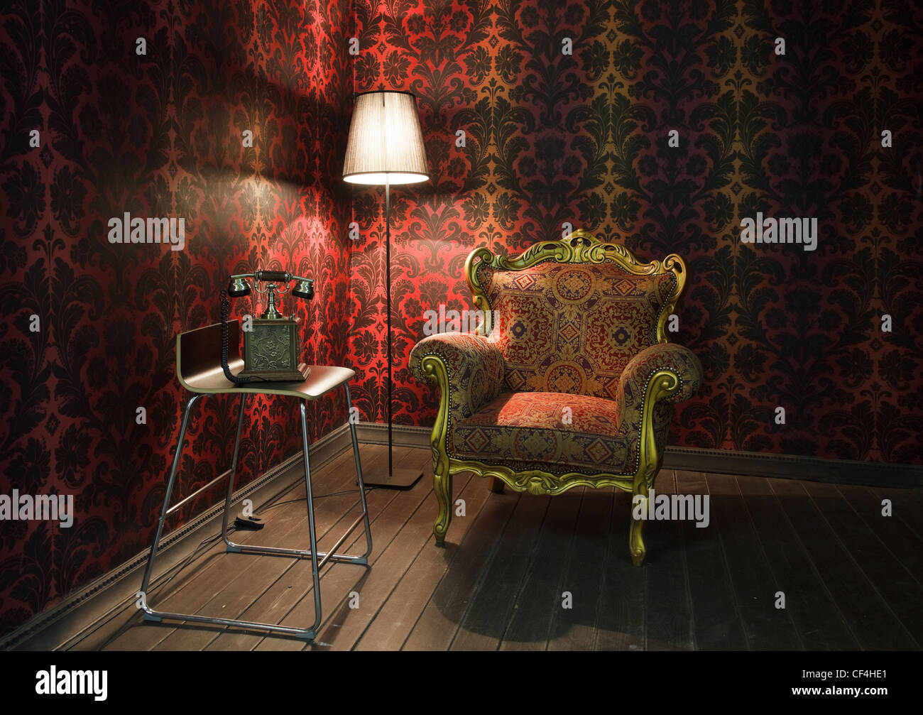 corner of the room with red wallpaper, floor lamp and armchair. Old phone on the chair Stock Photo