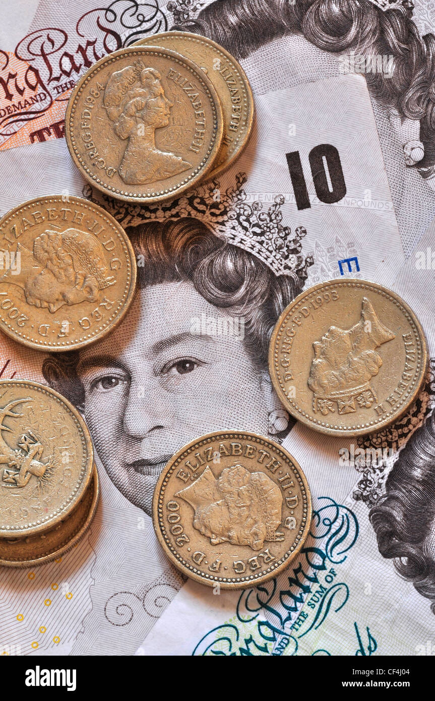 Pound coins lying on notes, UK money Stock Photo