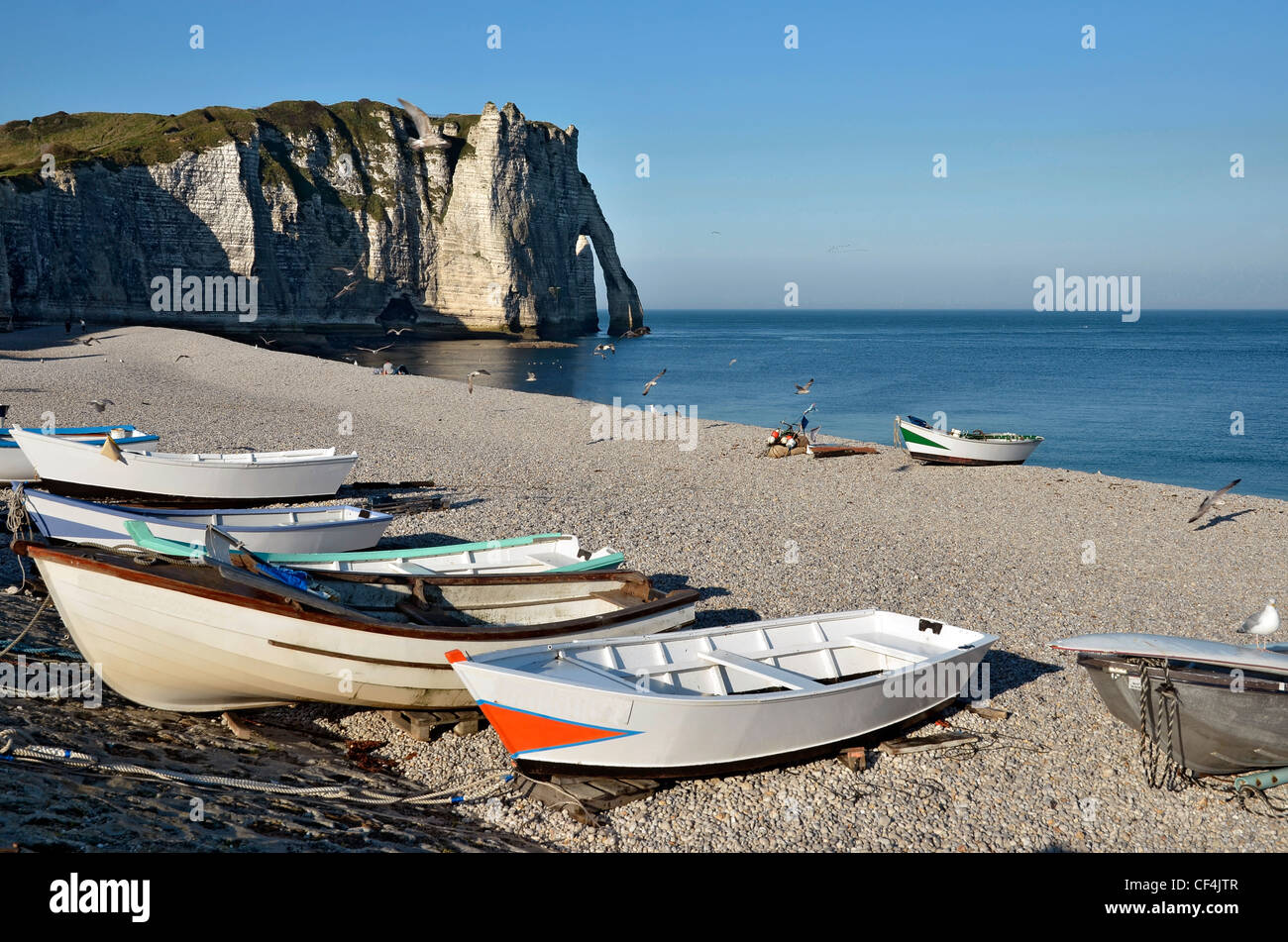 Small fishing boats on the famous pebble beach and cliffs of Etretat in ...