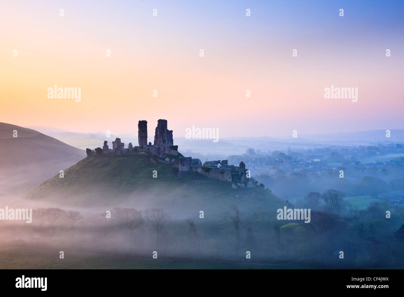 Corfe Castle, dating back to the 11th century, shrouded in mist at sunrise. Stock Photo