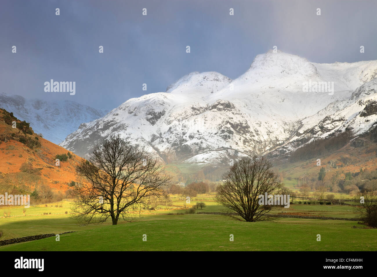 View along the Langdale valley towards the snow capped Langdale pikes on a stormy winters day. Stock Photo