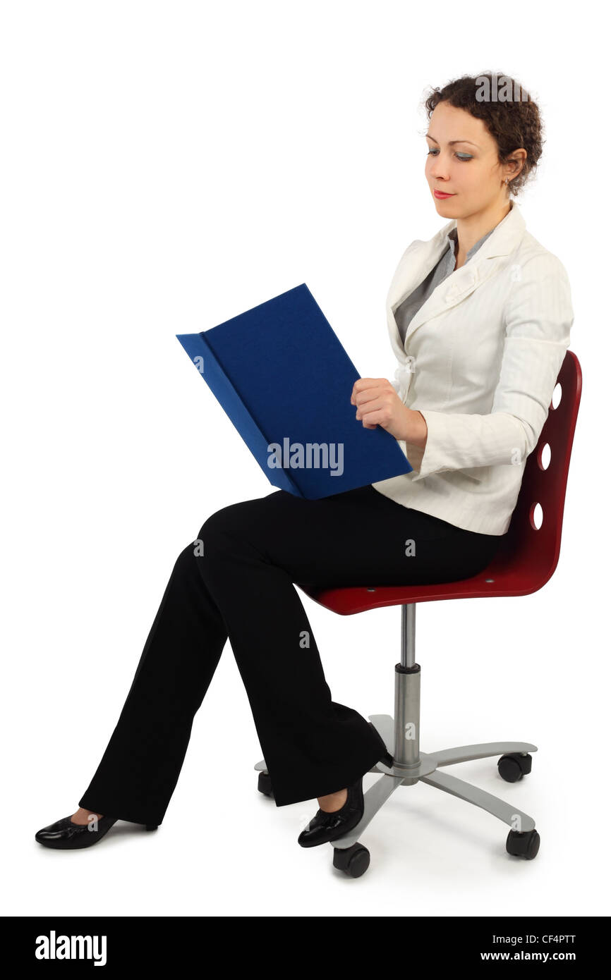 young attractive woman in business dress sitting on chair and reading a book, side view, isolated on white Stock Photo