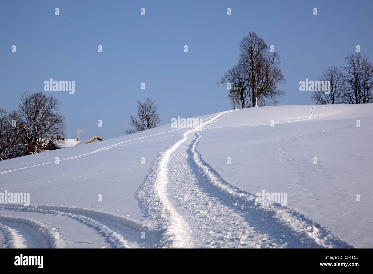 Snowy track leading to hill with wooden cross Buchberg near Bad Toelz Bavaria Germany Europe Stock Photo