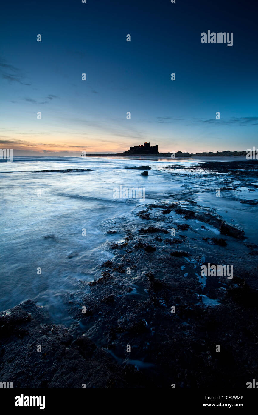 View along the coast at dawn towards Bamburgh Castle, former home to the Kings of Northumbria. Stock Photo