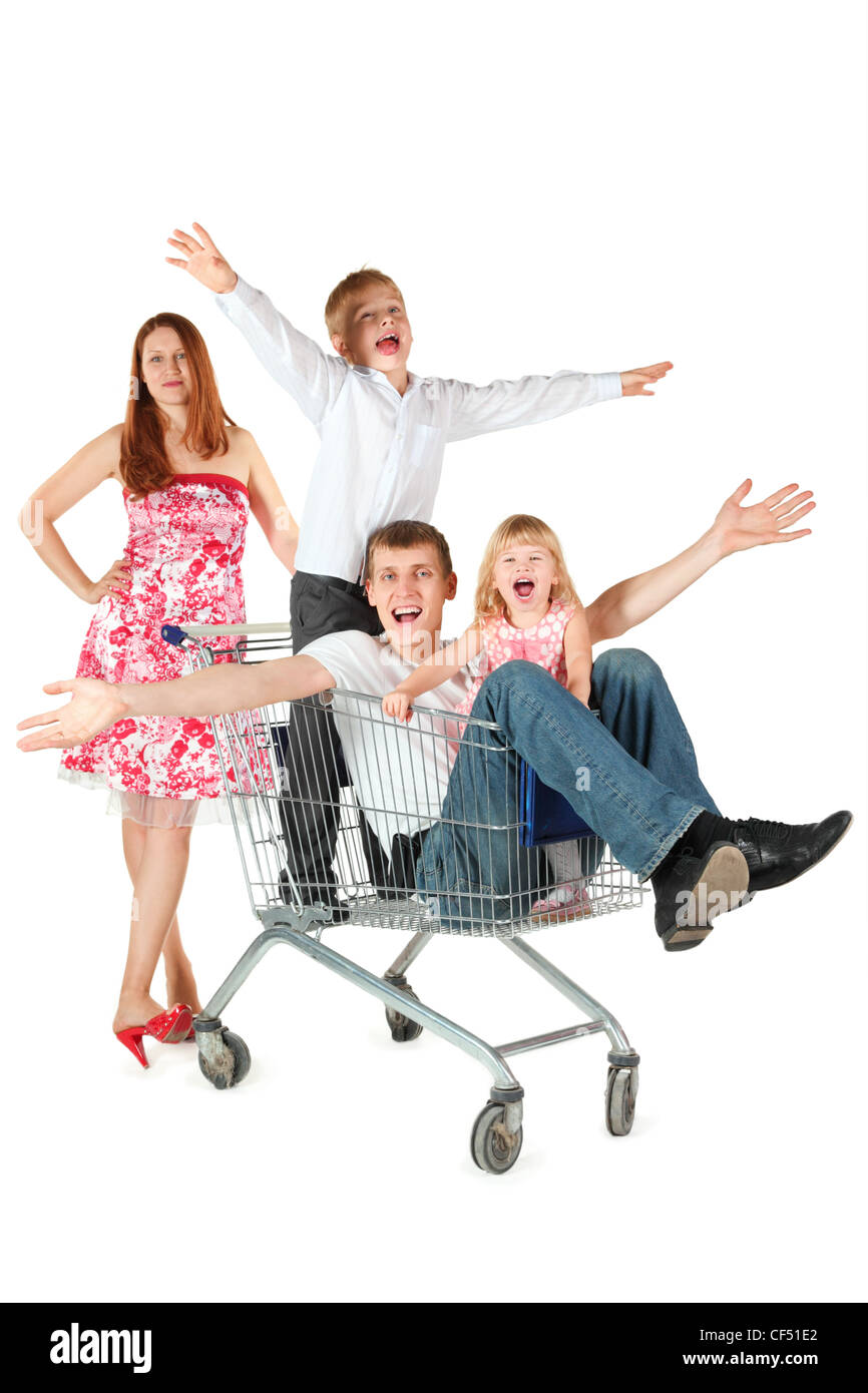 family two children joyful father son daughter is sitting in shopping basket mother is standing behind shopping basket isolated. Stock Photo