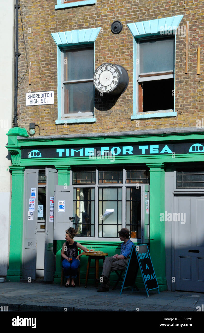 A young couple sitting outside Time for Tea tea shop in Shoreditch High Street. Stock Photo
